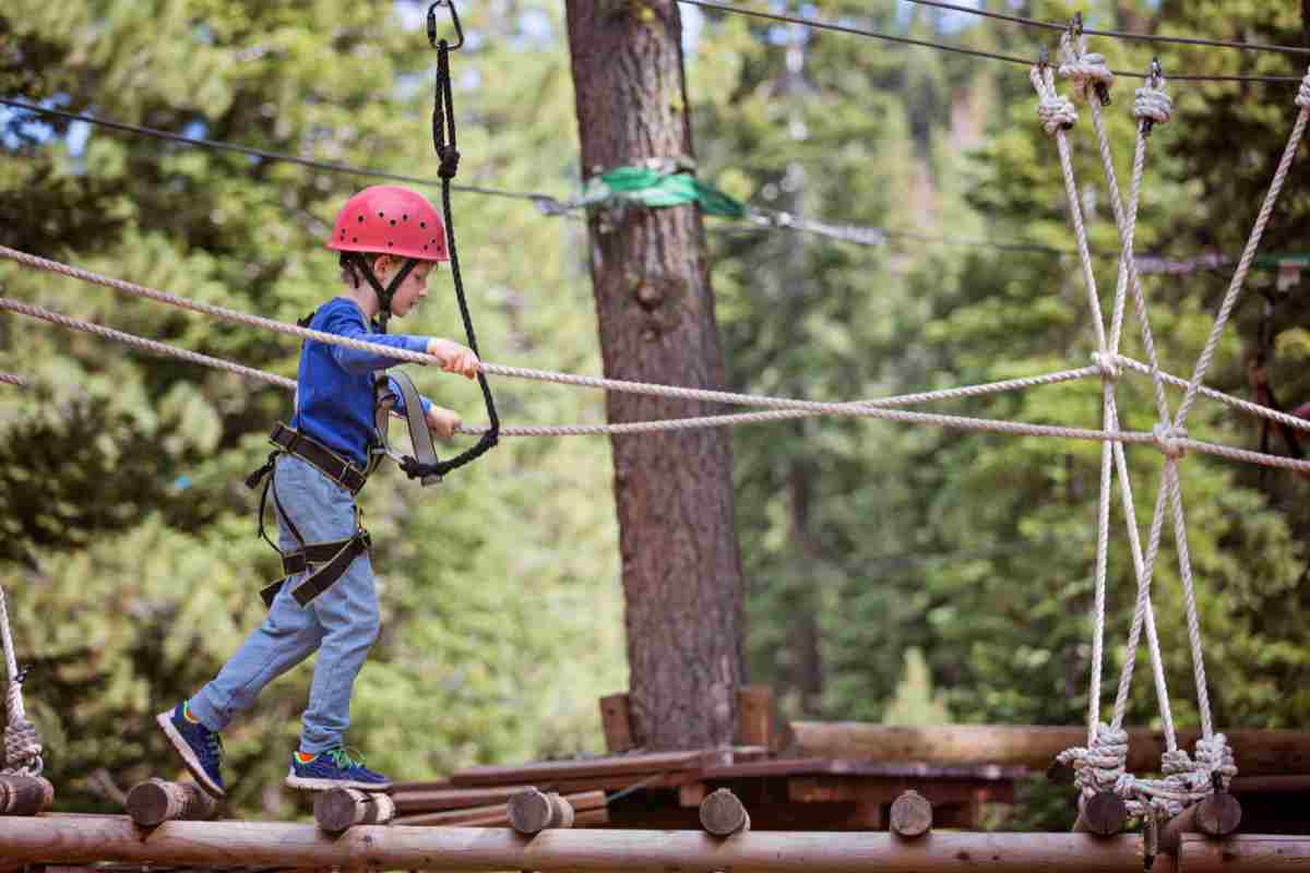 un bambino su un ponte di legno in un parco avventura