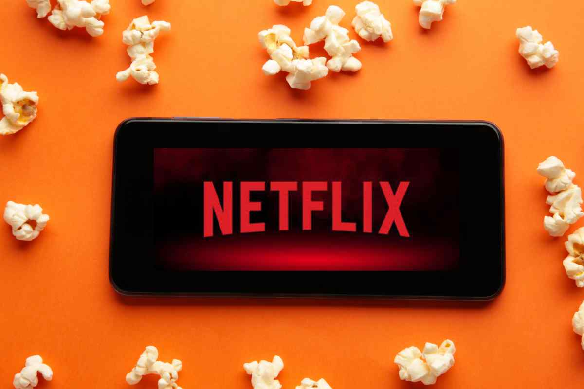 smartphone con logo netflix e pop corn su sfondo arancione