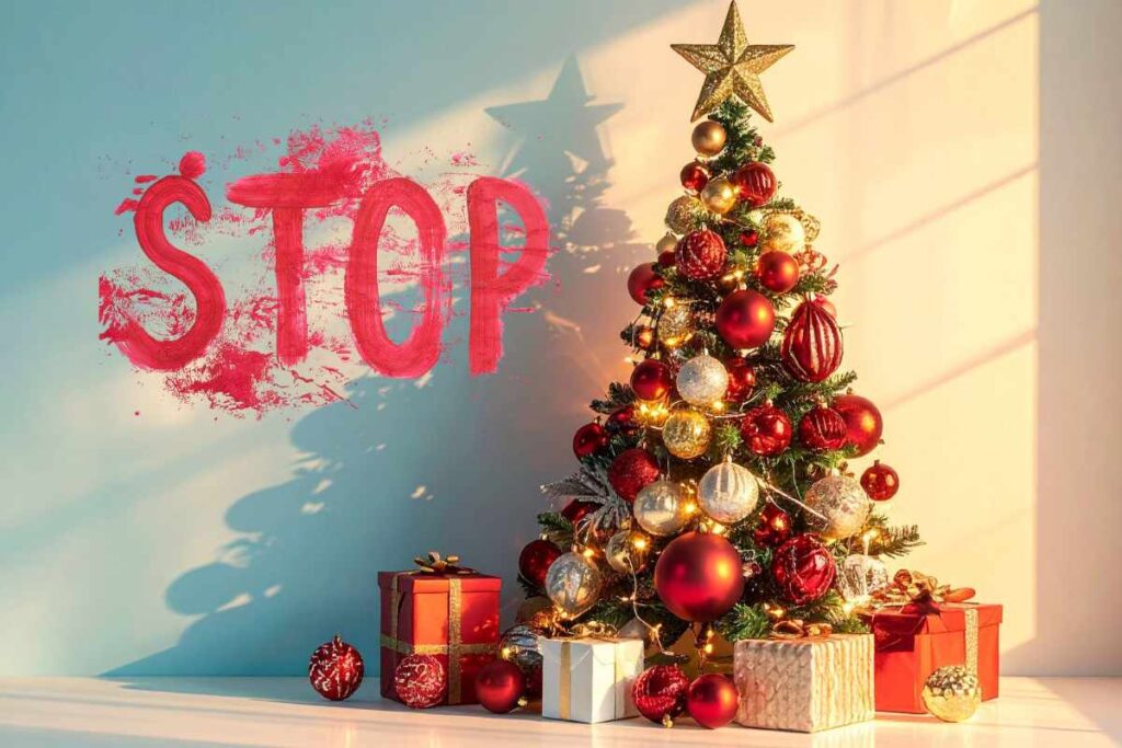Una scritta "Stop" sul muro in rosso accanto ad un albero di natale decorato