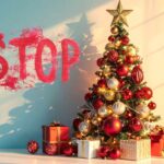 Una scritta "Stop" sul muro in rosso accanto ad un albero di natale decorato