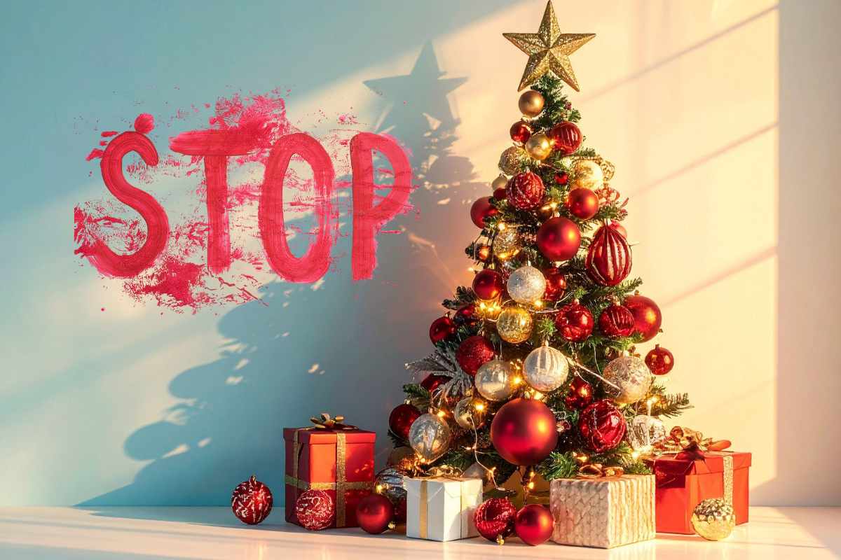 Una scritta "Stop" sul muro in rosso accanto ad un albero di natale decorato