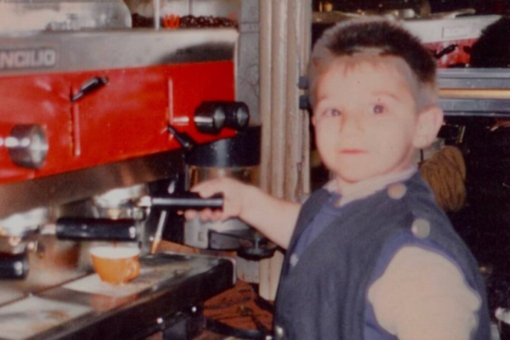 Una foto di un bambino davanti alla macchina del caffè