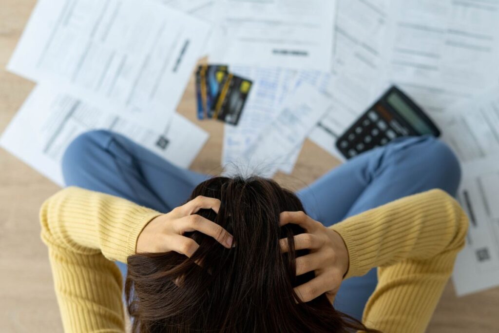 Una persona con le mani tra i capelli preche guarda le bollette che deve pagare