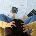 Una persona con le mani tra i capelli preche guarda le bollette che deve pagare
