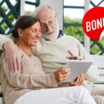 Due pensionati che vedono un tablet ed una scritta bonus in alto a destra