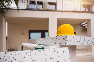 Il materiale per il cappotto termico di fronte ad una casa ed un elmetto per lavoratori