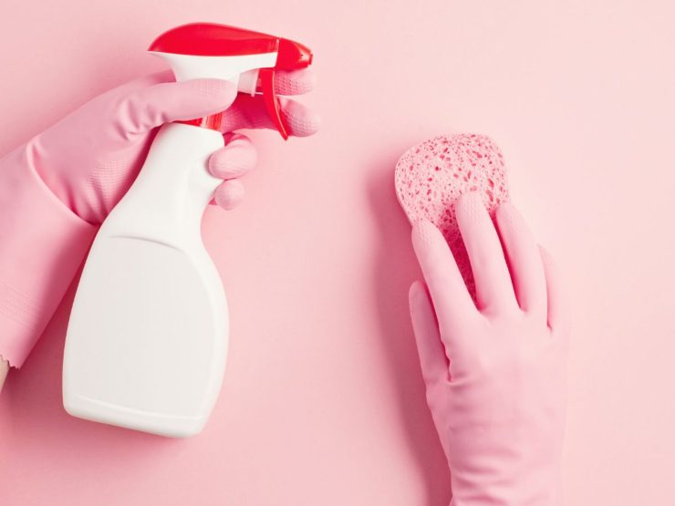 mani che puliscono con spray e spugnetta