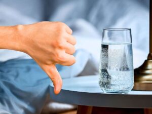 sfondo bicchiere d'acqua sul comodino e pollice in giù
