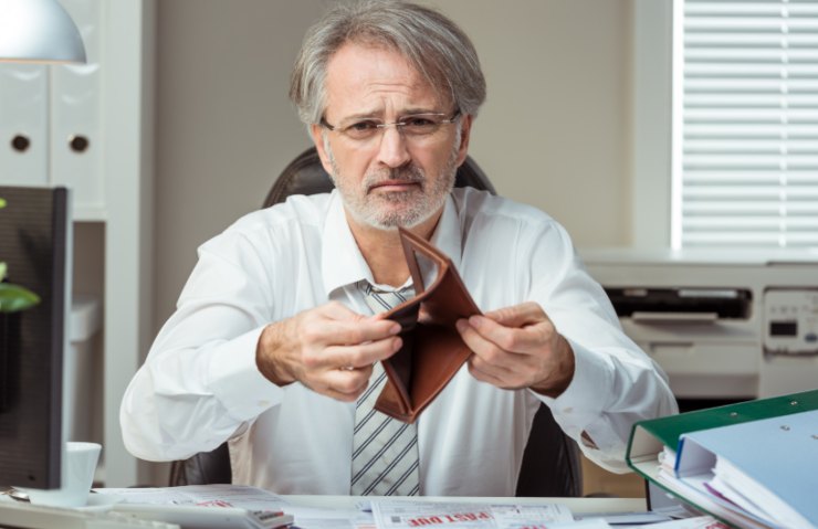 uomo con espressione triste che mostra un portafoglio vuoto