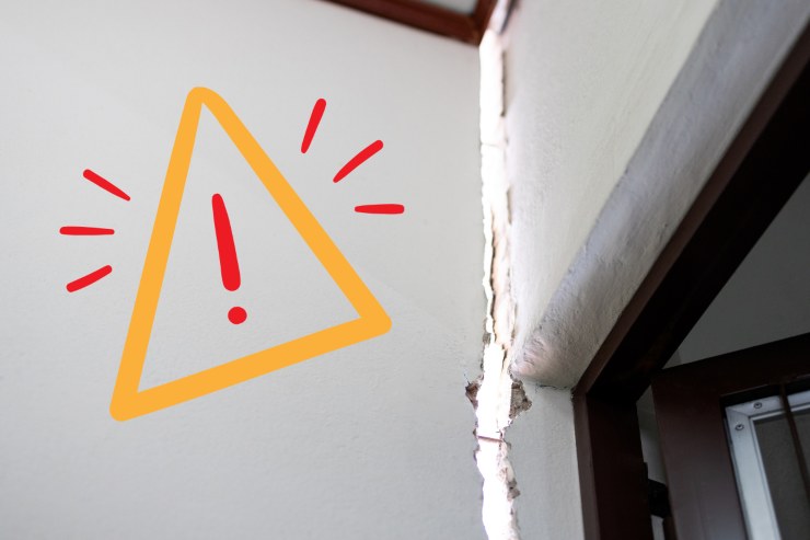 Una crepa sul muro di una casa ed un segnale di pericolo sulla sinistra