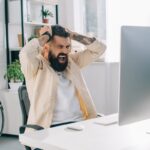 Una persona che guarda il proprio computer e si dispera e mette le mano tra i capelli