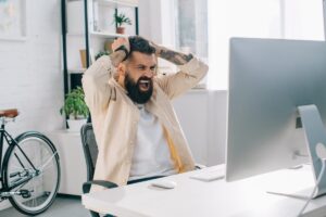 Una persona che guarda il proprio computer e si dispera e mette le mano tra i capelli