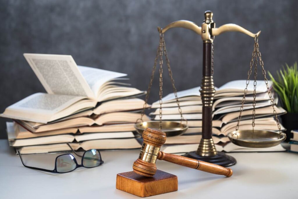 dei libri di legge sullo sfondo e davanti una bilancia di giustizia ed un martello da giudice