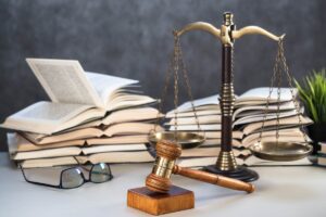 dei libri di legge sullo sfondo e davanti una bilancia di giustizia ed un martello da giudice