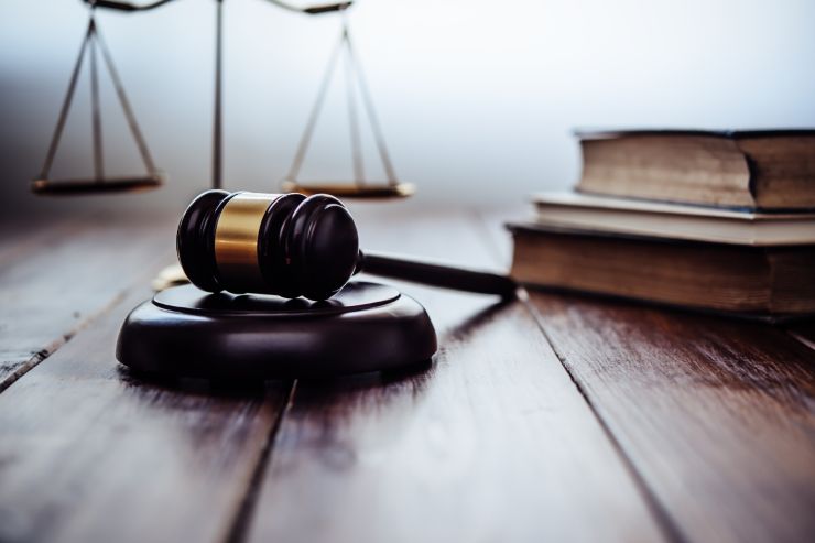 Uno sfondo con una bilancia e dei libri di legge e un martello da giudice