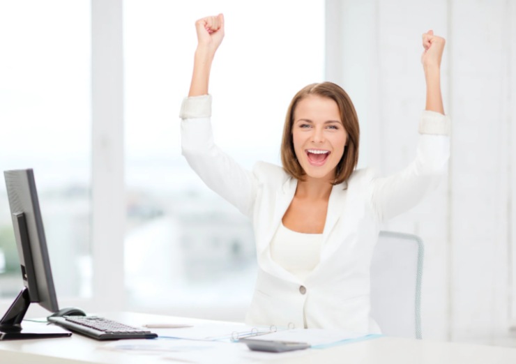 donna davanti al computer che esulta con le braccia in alto