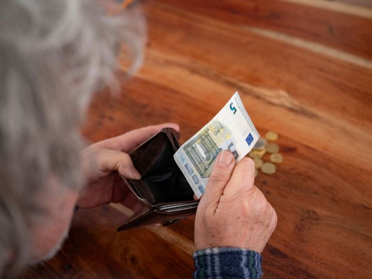 persona tira fuori banconota 5 euro da portafoglio 