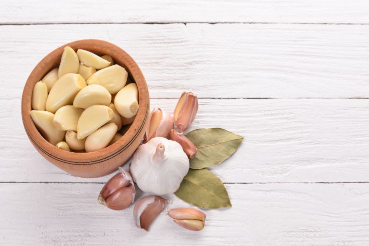 Una ciotola di spicchi di aglio pelati ed aglio fuori dalla ciotola