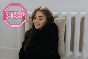 Una persona sdraiata su un termosifone ed un segnale di stop in alto a sinistra