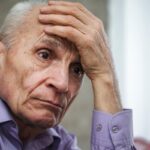 uomo anziano triste con una mano sulla fronte