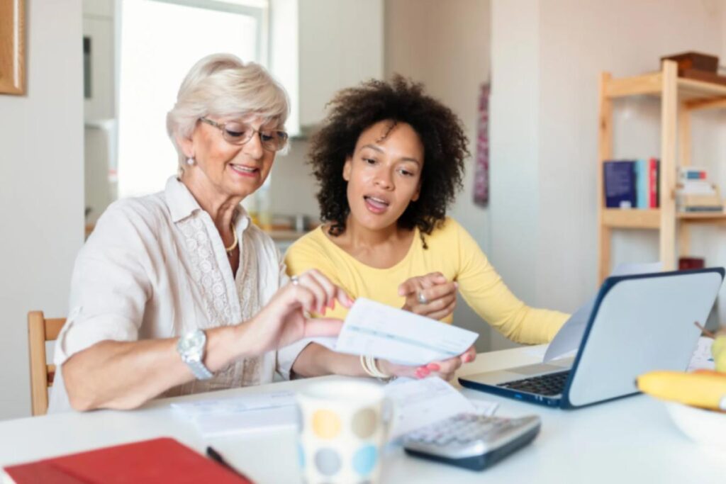 due donne che sorridono mentre leggono una bolletta davanti al computer