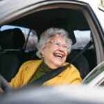 donna anziana che sorride mentre guida l'auto