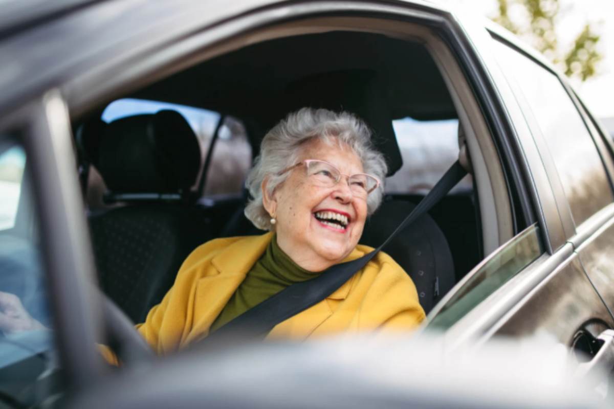donna anziana che sorride mentre guida l'auto