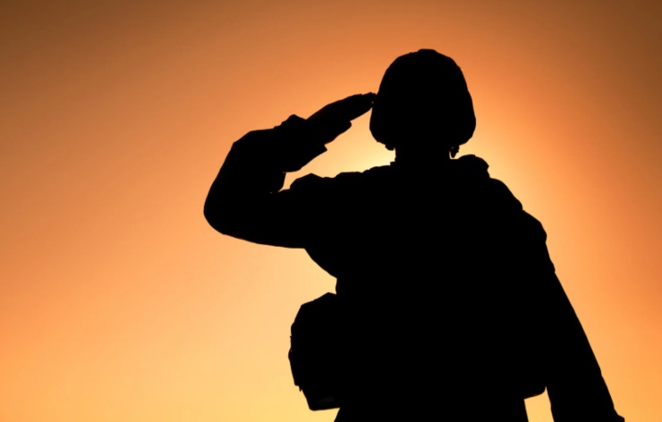 sagoma di un soldato che fa il saluto militare e dietro la luce del tramonto
